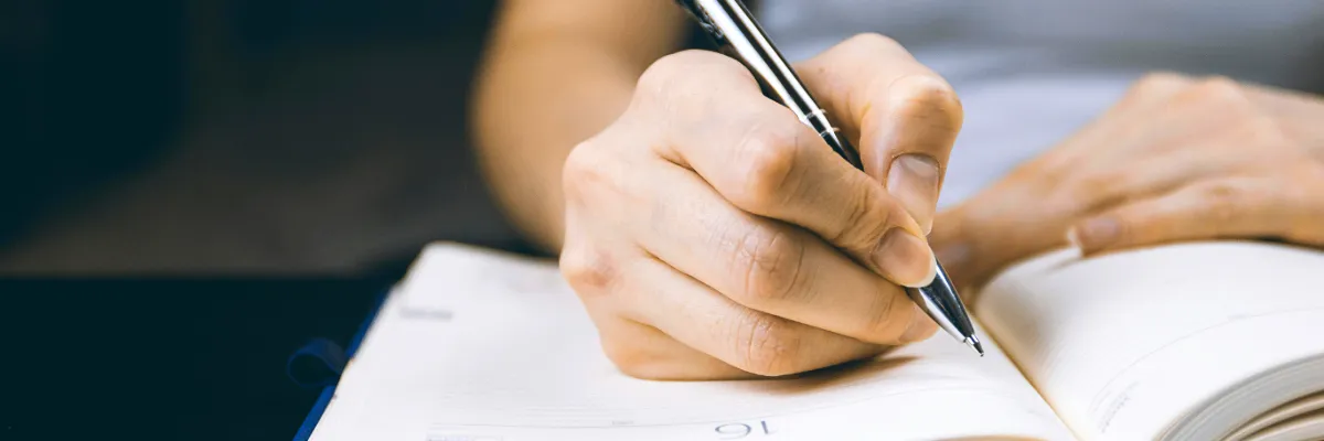 ahb_bodywork-intake-assessment Woman's hand writing illustrating a bodywork intake consultation, assessment, and a treatment plan for emotional healing
